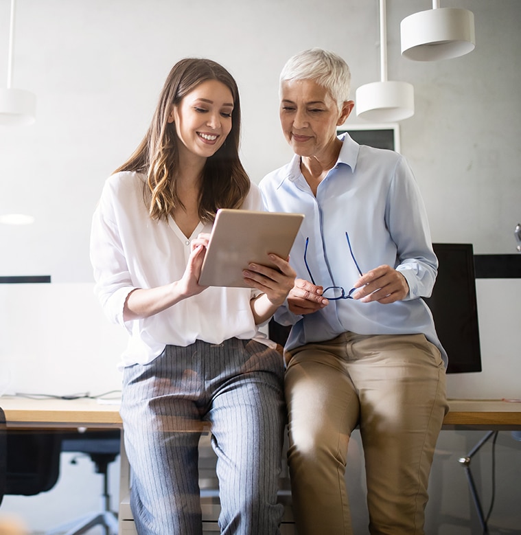 Two businesswomen looking at a tablet in a modern office